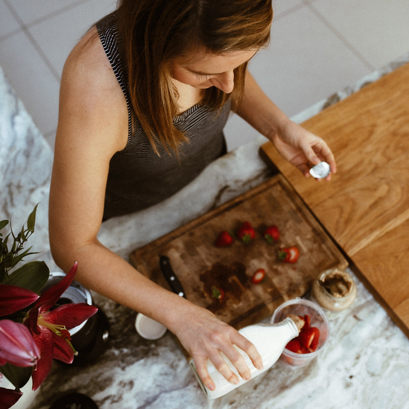 Fit lady preparing a meal in new kitchen. Strawberries and smoothie